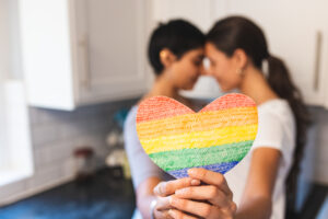 Lesbian couple holding rainbow pride month heart