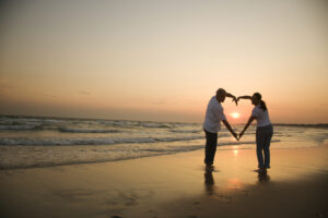 couple on beach with heart hands